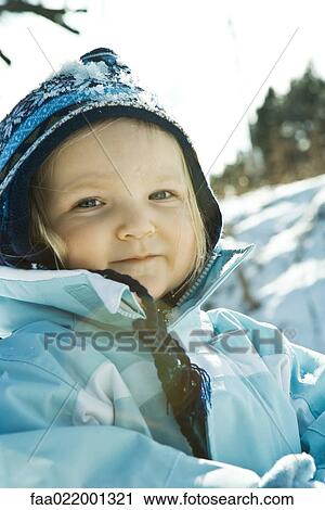 Stock Image - Toddler girl wearing winter clothes in snowy landscape, portrait. Fotosearch