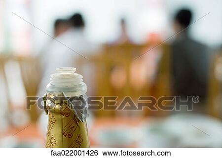 Stock Photograph - Top of sauce bottle, diners in background. Fotosearch