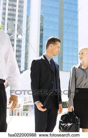 Two business associates standing on sidewalk, looking at each other, discussing View Large Photo Image Stock Photo - Two business associates standing on sidewalk, looking at each other, discussing. Fotosearch