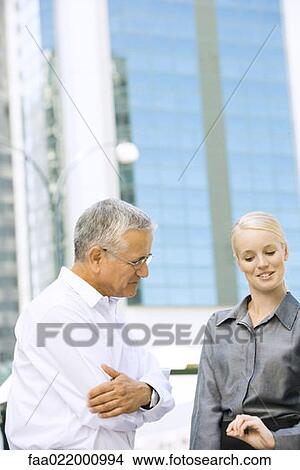 Two business associates standing outdoors, chatting, waist up View Large Photo Image Picture - Two business associates standing outdoors, chatting, waist up. Fotosearch
