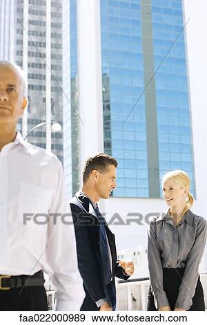 Stock Photo - Two business associates standing outdoors, discussing, mature man in foreground. Fotosearch