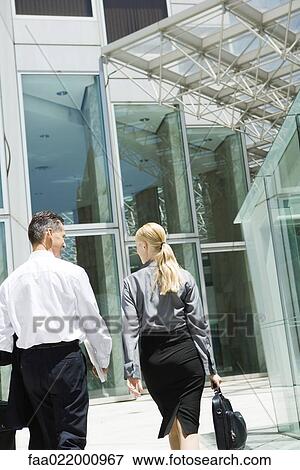 Two business associates walking toward building together, rear view View Large Photo Image Stock Photo - Two business associates walking toward building together, rear view. Fotosearch