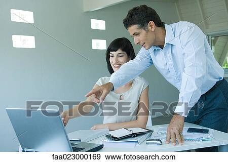 Two business colleagues looking at computer monitor, pointing to screen View Large Photo Image Stock Photo - Two business colleagues looking at computer monitor, pointing to screen. Fotosearch