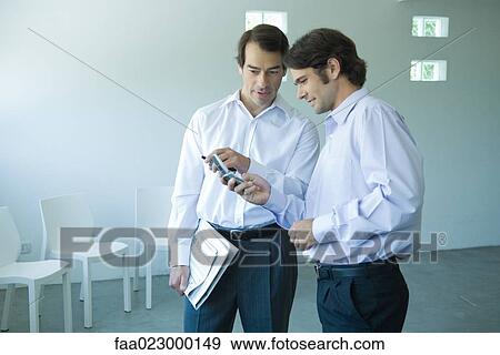 Two businessmen looking at cell phone together View Large Photo Image Stock Photo - Two businessmen looking at cell phone together. Fotosearch