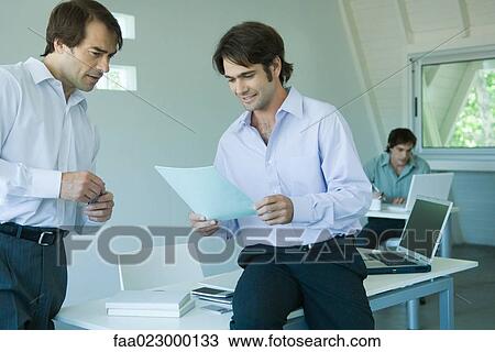 Two businessmen looking at document together in office View Large Photo Image Stock Image - Two businessmen looking at document together in office. Fotosearch