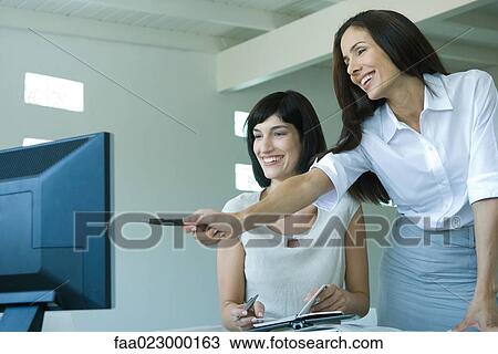 Two businesswomen looking at computer monitor together, one pointing View Large Photo Image Stock Image - Two businesswomen looking at computer monitor together, one pointing. Fotosearch