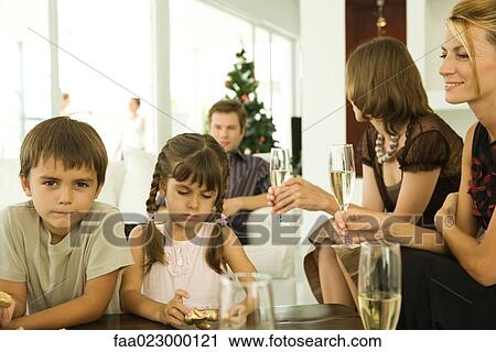 Two children holding Christmas ornaments, adults drinking champagne View Large Photo Image Stock Image - Two children holding Christmas ornaments, adults drinking champagne. Fotosearch