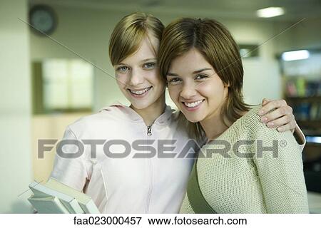 Two female college students, one with arm around the other's shoulders, smiling at camera, portrait View Large Photo Image Stock Photo - Two female college students, one with arm around the other's shoulders, smiling at camera, portrait. Fotosearch