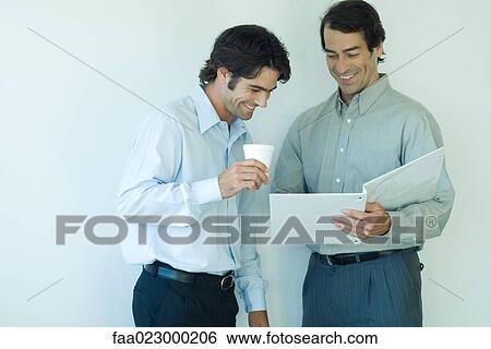 Two male colleagues looking at file together, laughing View Large Photo Image Stock Photograph - Two male colleagues looking at file together, laughing. Fotosearch