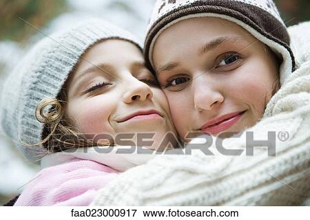 Two sisters embracing, smiling, one closing eyes, the other looking at camera, portrait View Large Photo Image Stock Photo - Two sisters embracing, smiling, one closing eyes, the other looking at camera, portrait. Fotosearch
