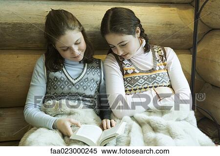 Two teen girls in winter clothes sitting under warm blanket together, reading View Large Photo Image Stock Photography - Two teen girls in winter clothes sitting under warm blanket together, reading. Fotosearch