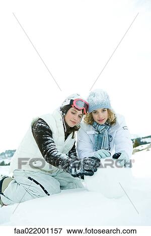 Two teenage girls crouching in snow, building snowball together, one smiling at camera View Large Photo Image Stock Photo - Two teenage girls crouching in snow, building snowball together, one smiling at camera. Fotosearch