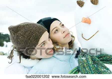 Two teenage girls looking at snowman together, one's head on the other's shoulder View Large Photo Image Stock Image - Two teenage girls looking at snowman together, one's head on the other's shoulder. Fotosearch