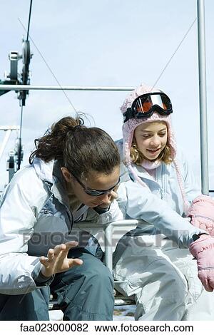Two teenage girls sitting on chair lift together, looking over side View Large Photo Image Stock Image - Two teenage girls sitting on chair lift together, looking over side. Fotosearch