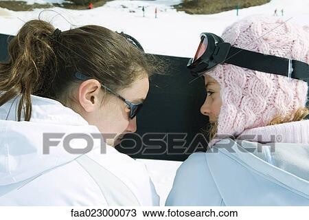 Two teenage girls sitting side by side, looking at each other, rear view View Large Photo Image Stock Image - Two teenage girls sitting side by side, looking at each other, rear view. Fotosearch