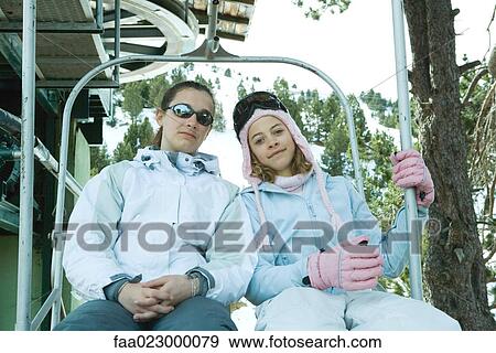 Two teenage girls sitting together on chair lift, smiling at camera View Large Photo Image Stock Photo - Two teenage girls sitting together on chair lift, smiling at camera. Fotosearch