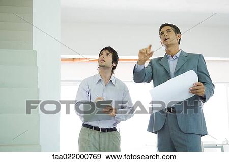 Two well-dressed men inspecting house, looking up View Large Photo Image Stock Photo - Two well-dressed men inspecting house, looking up. Fotosearch