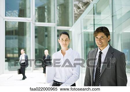 Two young business associates smiling at camera, waist up, portrait View Large Photo Image Stock Photography - Two young business associates smiling at camera, waist up, portrait. Fotosearch