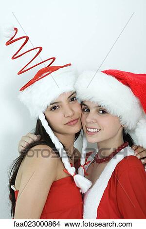 Two young female friends dressed in Christmas costumes, cheek to cheek, smiling at camera, portrait View Large Photo Image Picture - Two young female friends dressed in Christmas costumes, cheek to cheek, smiling at camera, portrait. Fotosearch