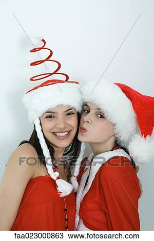 Stock Image - Two young female friends dressed in Christmas costumes, portrait. Fotosearch