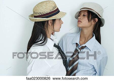 Two young female friends dressed in button down shirts, ties and hats, face to face, portrait View Large Photo Image Stock Photograph - Two young female friends dressed in button down shirts, ties and hats, face to face, portrait. Fotosearch