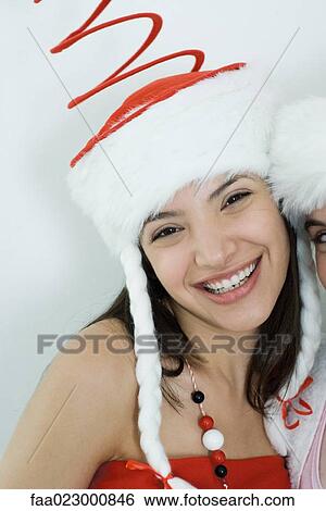 Two young female friends dressed in Christmas costumes, smiling at camera, portrait, cropped View Large Photo Image Stock Photograph - Two young female friends dressed in Christmas costumes, smiling at camera, portrait, cropped. Fotosearch