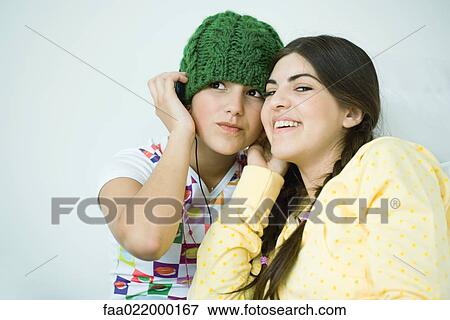 Two young female friends listening to headphones View Large Photo Image Stock Photo - Two young female friends listening to headphones. Fotosearch