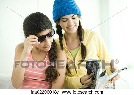 Two young female friends looking in magazine together View Large Photo Image Stock Photo - Two young female friends looking in magazine together. Fotosearch