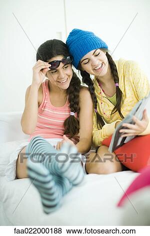 Two young female friends looking in magazine together View Large Photo Image Stock Photo - Two young female friends looking in magazine together. Fotosearch