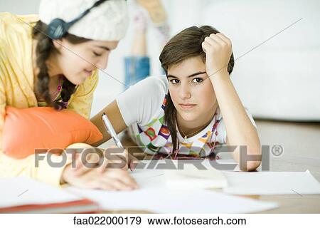 Two young female friends lying on floor, doing homework together View Large Photo Image Stock Photo - Two young female friends lying on floor, doing homework together. Fotosearch