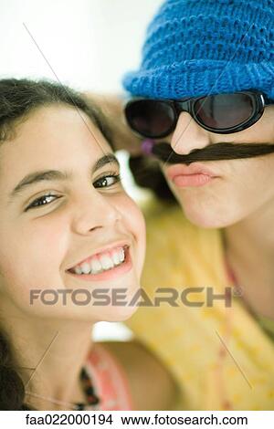 Two young female friends, one holding hair below nose like mustache, portrait View Large Photo Image Picture - Two young female friends, one holding hair below nose like mustache, portrait. Fotosearch