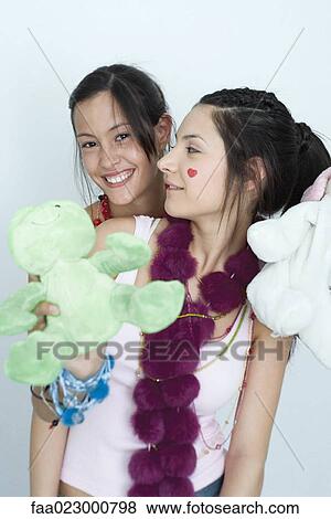 Two young female friends, one holding stuffed animals, looking at camera, portrait View Large Photo Image Stock Photo - Two young female friends, one holding stuffed animals, looking at camera, portrait. Fotosearch