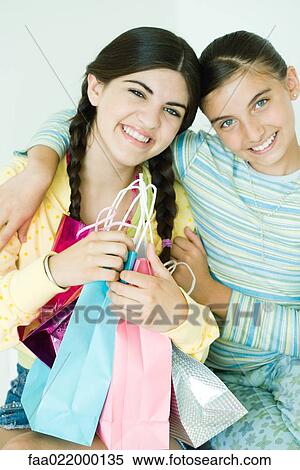 Two young female friends, one holding gift bags View Large Photo Image Stock Photography - Two young female friends, one holding gift bags. Fotosearch