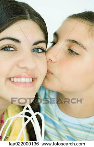 Stock Photograph - Two young female friends, one kissing the other on the cheek. Fotosearch