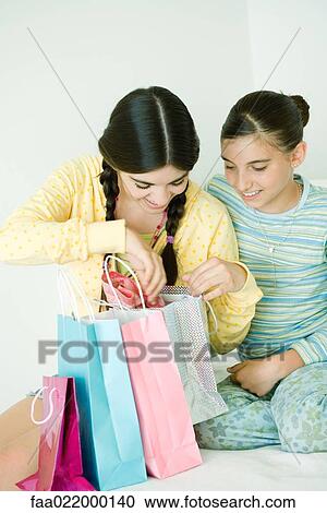 Two young female friends, one opening up gift bags View Large Photo Image Stock Image - Two young female friends, one opening up gift bags. Fotosearch