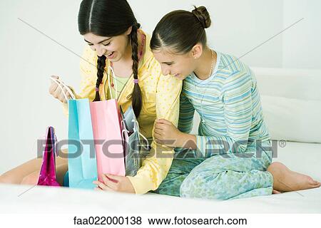 Two young female friends, one opening up gift bags View Large Photo Image Stock Photo - Two young female friends, one opening up gift bags. Fotosearch