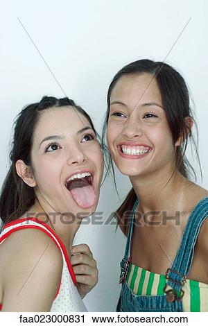 Two young female friends, one sticking tongue out, the other laughing, portrait View Large Photo Image Stock Image - Two young female friends, one sticking tongue out, the other laughing, portrait. Fotosearch