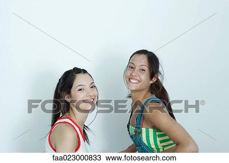 Two young female friends, smiling at camera, portrait View Large Photo Image Stock Image - Two young female friends, smiling at camera, portrait. Fotosearch
