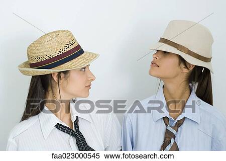 Two young female friends wearing hats and ties, looking at each other, portrait View Large Photo Image Stock Photography - Two young female friends wearing hats and ties, looking at each other, portrait. Fotosearch