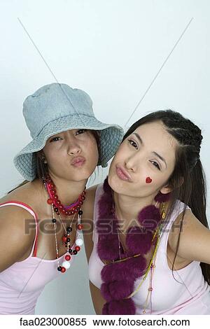Stock Photography - Two young female friends wearing lots of accessories, puckering at camera, portrait. Fotosearch