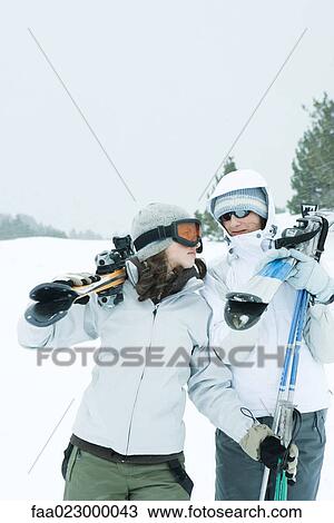 Two young friends carrying skis on shoulders, looking at each other View Large Photo Image Stock Image - Two young friends carrying skis on shoulders, looking at each other. Fotosearch
