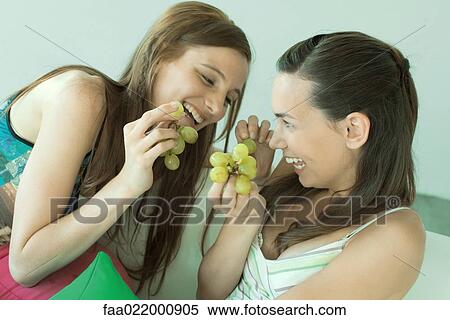 Two young friends eating grapes, laughing View Large Photo Image Stock Photography - Two young friends eating grapes, laughing. Fotosearch