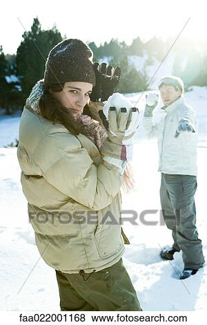 Stock Photo - Two young friends holding up snowballs, one looking over shoulder at camera. Fotosearch