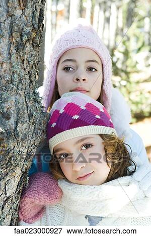 Two young friends leaning against tree trunk, dressed in winter clothing, one looking at camera View Large Photo Image Stock Photo - Two young friends leaning against tree trunk, dressed in winter clothing, one looking at camera. Fotosearch