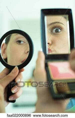 Two young friends looking at selves in hand mirrors, one making faces, cropped view View Large Photo Image Stock Photograph - Two young friends looking at selves in hand mirrors, one making faces, cropped view. Fotosearch