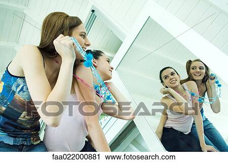 Two young friends looking at their reflections in mirror, smiling, one looking over the other's shoulder View Large Photo Image Stock Image - Two young friends looking at their reflections in mirror, smiling, one looking over the other's shoulder. Fotosearch