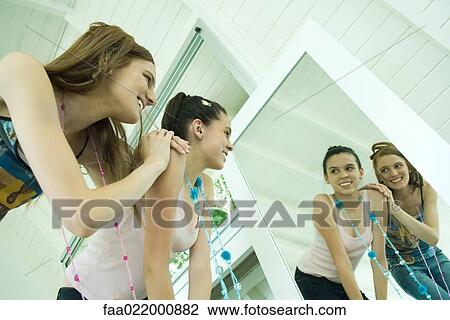 Two young friends looking at their reflections in mirror, smiling, one leaning on the other's shoulder View Large Photo Image Stock Image - Two young friends looking at their reflections in mirror, smiling, one leaning on the other's shoulder. Fotosearch