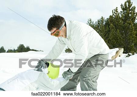 Two young friends playing in snow, one pulling the other up View Large Photo Image Picture - Two young friends playing in snow, one pulling the other up. Fotosearch
