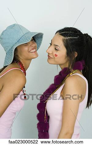 Two young friends standing face to face, smiling at each other View Large Photo Image Stock Image - Two young friends standing face to face, smiling at each other. Fotosearch