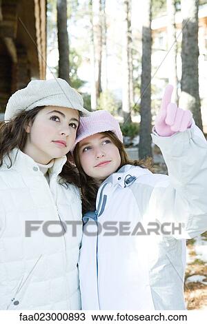 Two young friends standing together, cheek to cheek, looking up, one pointing View Large Photo Image Stock Image - Two young friends standing together, cheek to cheek, looking up, one pointing. Fotosearch